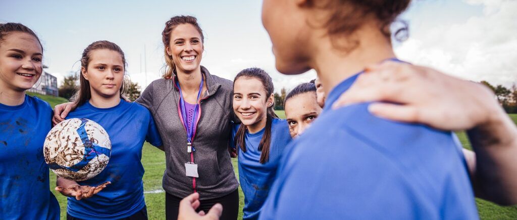 Female football coach talking to team on field