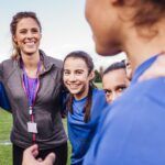 Female football coach talking to team on field