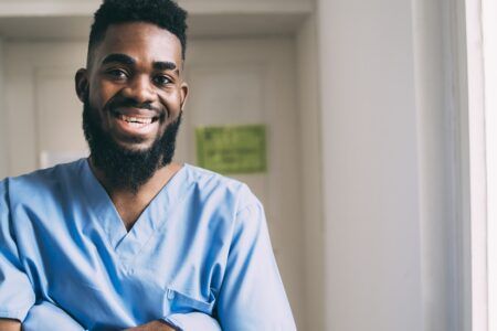 Male healthcare worker in blue scrubs smiling