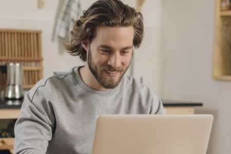 Man working at table on laptop smiling 2