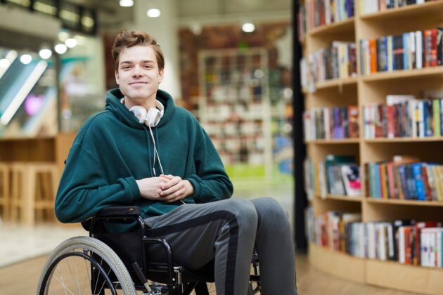 Student wheelchair user in library smiling