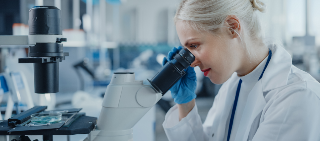 Woman looking through microscope in lab