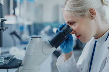 Woman looking through microscope in lab