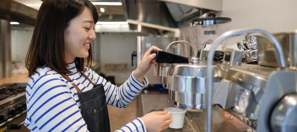 Woman making coffee for customer in cafe kitchen 1