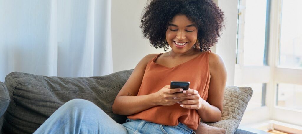 Woman smiling while using social media on phone