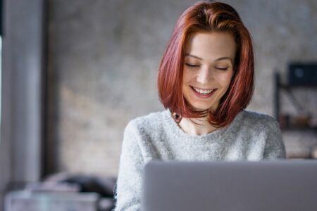 Woman working on laptop at home smiling