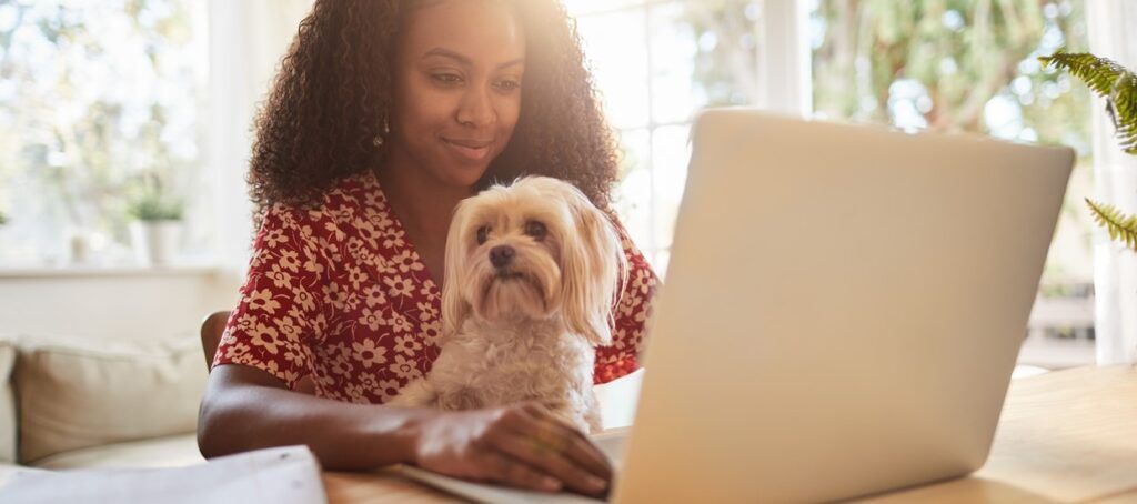 woman sitting at desk using laptop with a dog