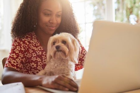 woman sitting at desk using laptop with a dog